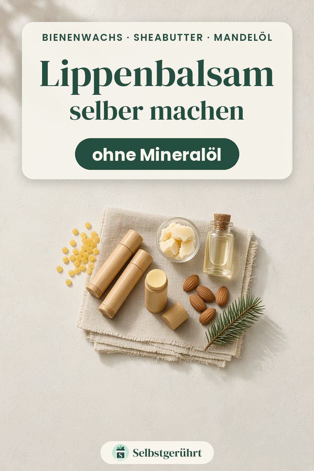 Flatlay auf hellem Untergrund: Leinentuch mit zwei Lippenbalsam-Hülsen mit Bambusschale, einem geöffneten Stift, gelben Bienenwachs-Pastillen, einem Glasschälchen mit Sheabutter-Stücken, einem Glasfläschchen mit Öl, Mandeln und einem Tannenzweig. Oben steht „Lippenbalsam selber machen – ohne Mineralöl“.